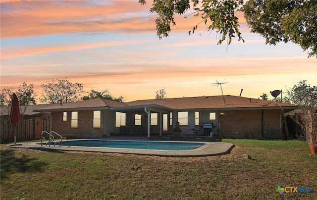 pool at dusk with a yard, a patio, and central AC unit