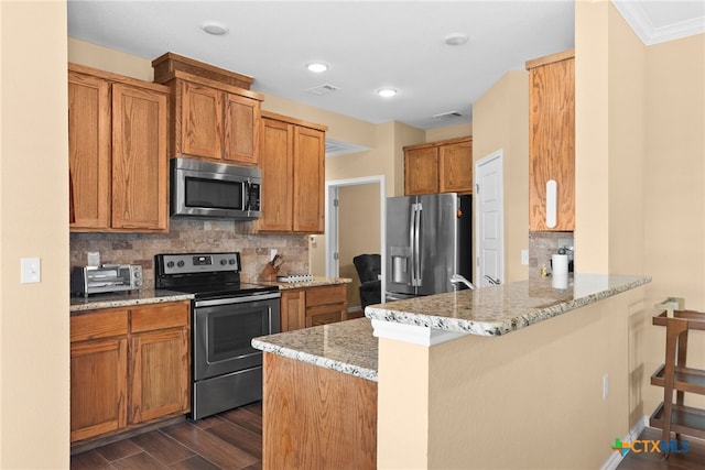 kitchen featuring appliances with stainless steel finishes, dark hardwood / wood-style floors, light stone countertops, decorative backsplash, and a breakfast bar