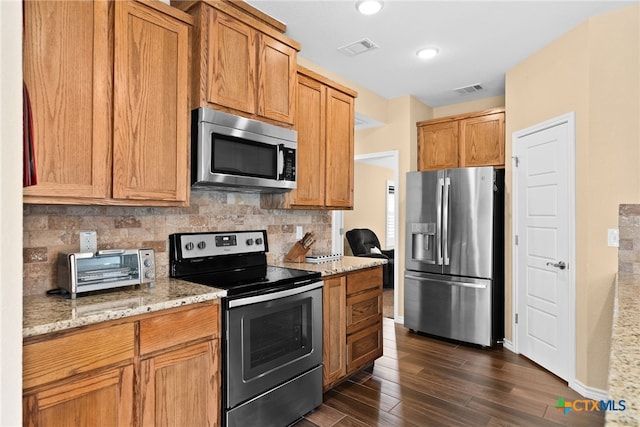 kitchen with stainless steel appliances, dark hardwood / wood-style floors, backsplash, and light stone counters