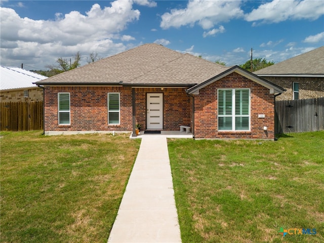 view of front of home with brick siding, fence, and roof with shingles