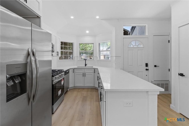 1701 Southwestern Trl, Round Rock, TX 78664 - kitchen with stainless steel appliances, light wood finished floors, a peninsula, light countertops, and recessed lighting
