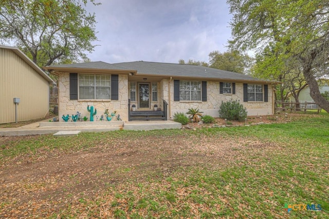 ranch-style house featuring a front yard, stone siding, and fence
