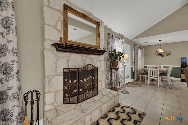 tiled living room featuring a notable chandelier, a stone fireplace, and lofted ceiling