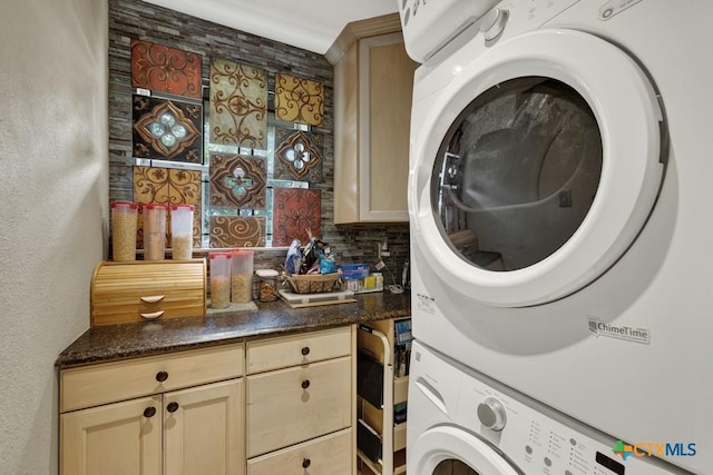 laundry room featuring stacked washer / drying machine and cabinet space