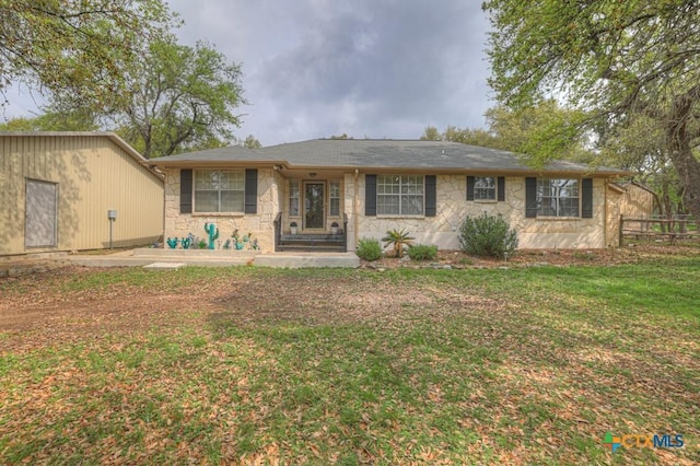 view of front of property with a front yard, fence, and stone siding