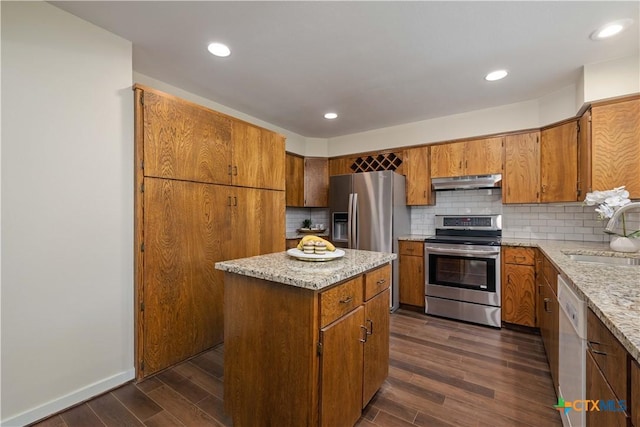 1143 Flaman Rd, Canyon Lake, TX 78133 - kitchen with stainless steel appliances, under cabinet range hood, dark wood finished floors, brown cabinets, and recessed lighting