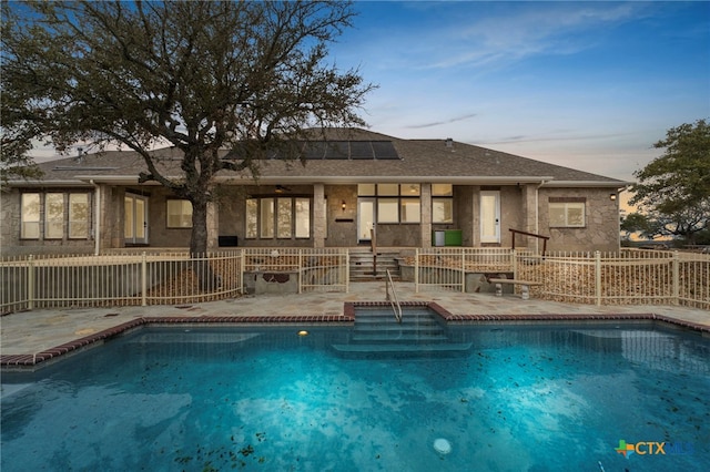 pool at dusk with ceiling fan, a patio, fence, and a fenced in pool