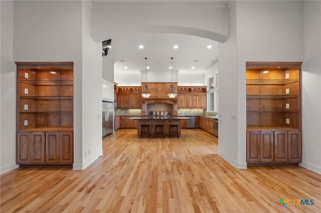 kitchen featuring brown cabinetry, light wood finished floors, stainless steel appliances, and a kitchen island