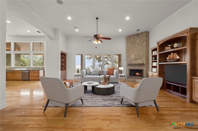 living room with a ceiling fan, a stone fireplace, a healthy amount of sunlight, and recessed lighting