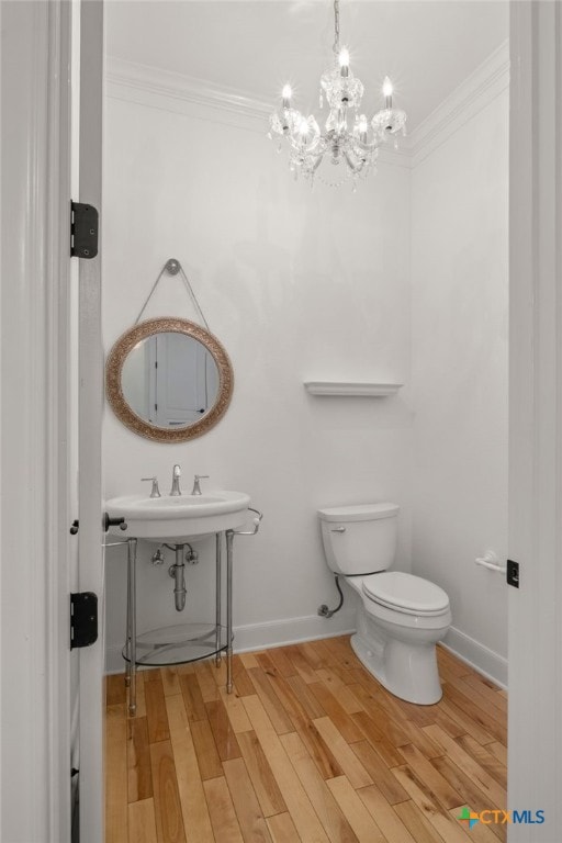 bathroom featuring a chandelier, ornamental molding, toilet, and wood finished floors