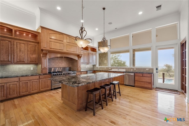 kitchen featuring a breakfast bar area, ornamental molding, visible vents, a kitchen island, and stainless steel appliances