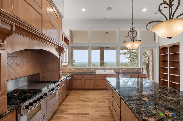 kitchen with brown cabinetry, light wood-type flooring, crown molding, hanging light fixtures, and appliances with stainless steel finishes