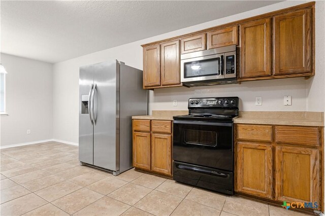 503 Chrislyn St, Troy, TX 76579 - kitchen featuring appliances with stainless steel finishes, light countertops, brown cabinetry, and light tile patterned floors