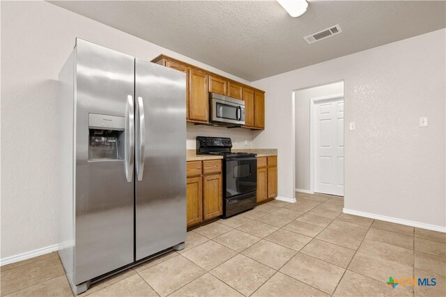 503 Chrislyn St, Troy, TX 76579 - kitchen featuring appliances with stainless steel finishes, brown cabinetry, light countertops, and light tile patterned flooring