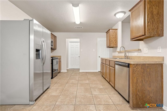 503 Chrislyn St, Troy, TX 76579 - kitchen with appliances with stainless steel finishes, light tile patterned floors, light countertops, a textured ceiling, and brown cabinets