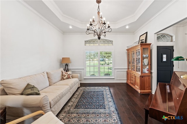 living room with an inviting chandelier, ornamental molding, and a tray ceiling