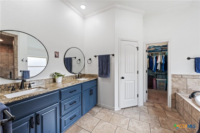 bathroom featuring tile patterned floors, a relaxing tiled tub, crown molding, and vanity