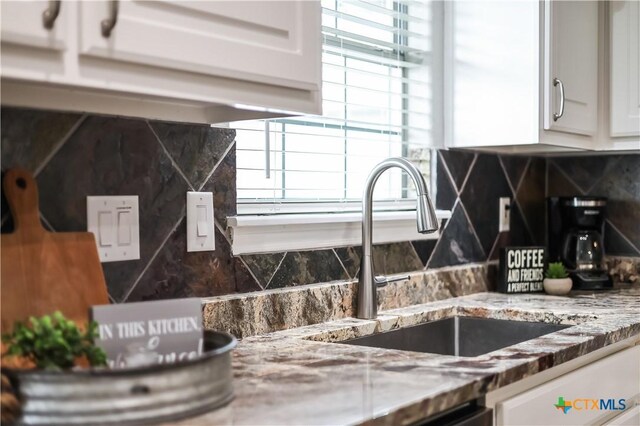 room details with white cabinetry, sink, decorative backsplash, and stone counters