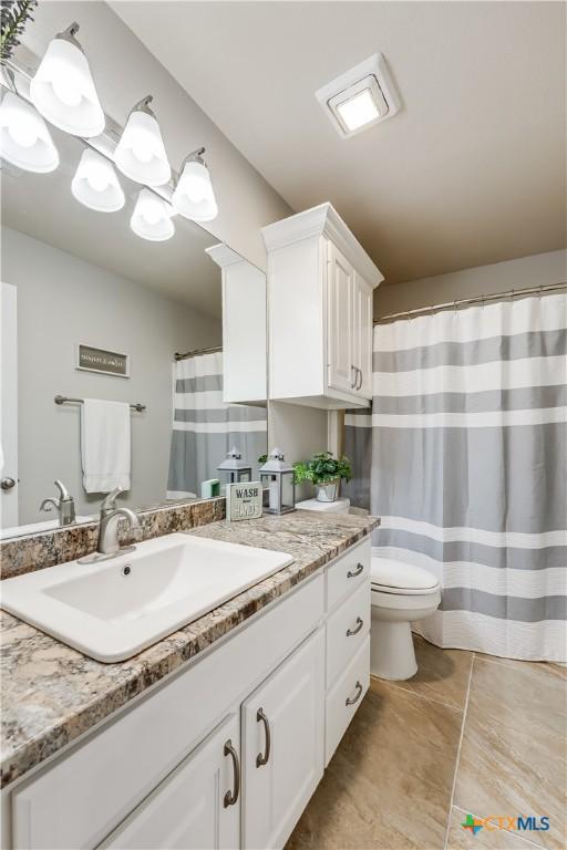 bathroom featuring vanity, tile patterned floors, toilet, and an inviting chandelier