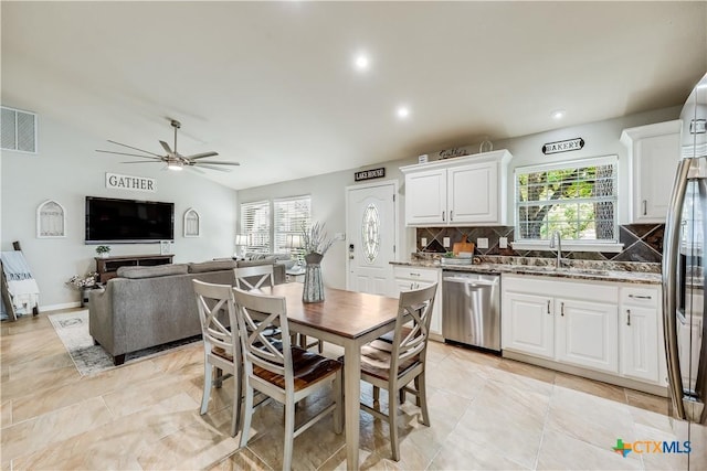 kitchen with lofted ceiling, tasteful backsplash, appliances with stainless steel finishes, dark stone counters, and white cabinets