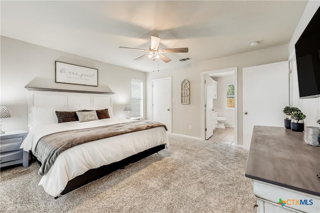 carpeted bedroom with ensuite bathroom and ceiling fan