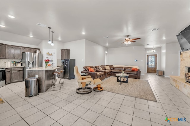 tiled living room featuring ceiling fan and a fireplace