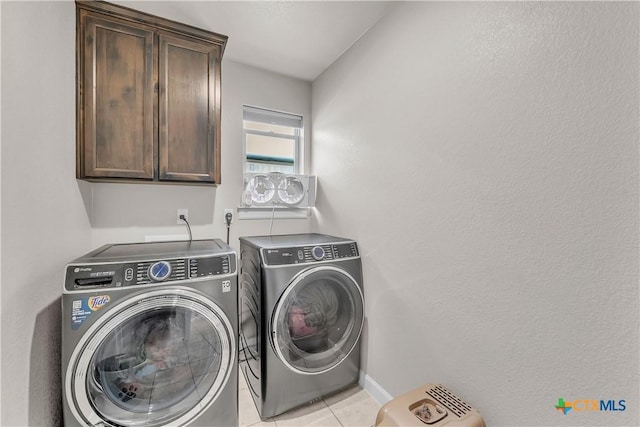 laundry area featuring independent washer and dryer, cabinets, and light tile patterned flooring