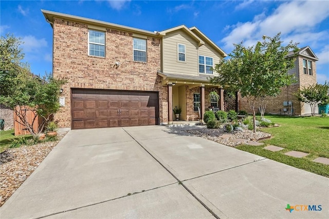 272 Adoquin Trl, Buda, TX 78610 - view of front of house with brick siding, an attached garage, concrete driveway, a front yard, and covered porch