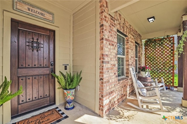 272 Adoquin Trl, Buda, TX 78610 - doorway to property featuring covered porch and brick siding
