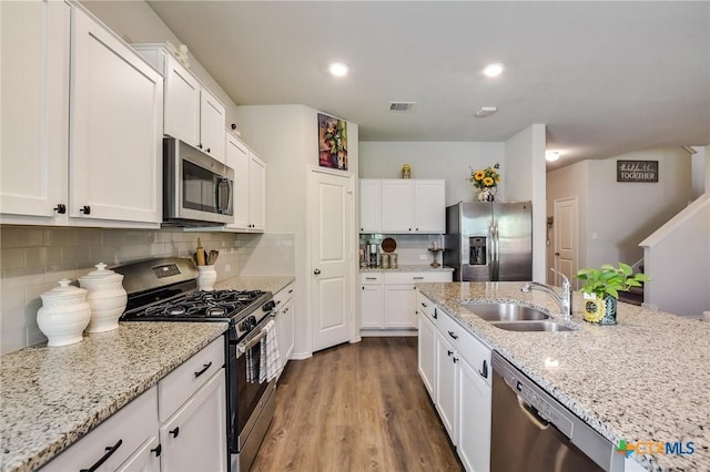 272 Adoquin Trl, Buda, TX 78610 - kitchen with appliances with stainless steel finishes, a sink, white cabinets, backsplash, and light stone countertops