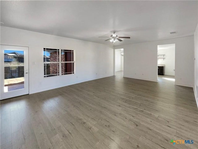 unfurnished living room with ceiling fan, wood finished floors, visible vents, and baseboards