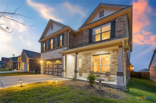 view of front of home with fence, a yard, concrete driveway, stone siding, and a garage