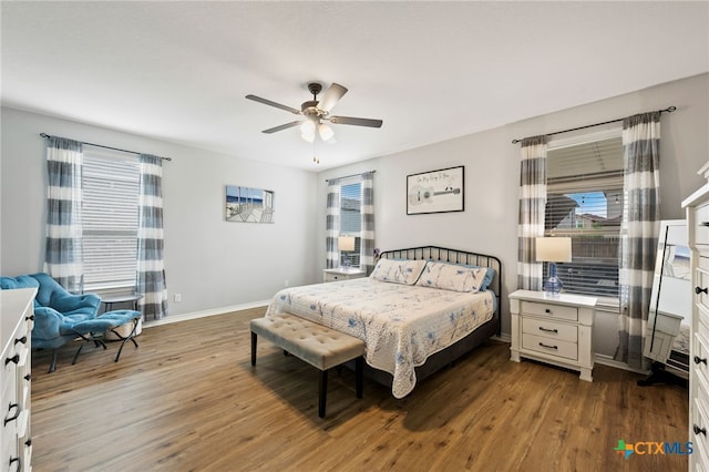 bedroom with wood finished floors, baseboards, and multiple windows