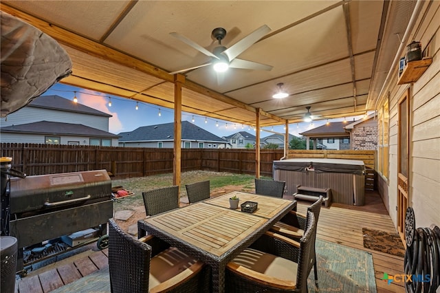 wooden terrace with a ceiling fan, outdoor dining space, a fenced backyard, grilling area, and a hot tub