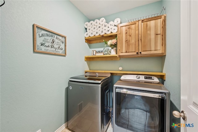 laundry area with cabinet space, a textured wall, baseboards, and separate washer and dryer