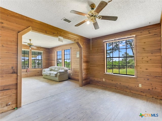 interior space with hardwood / wood-style floors, wood walls, and a textured ceiling