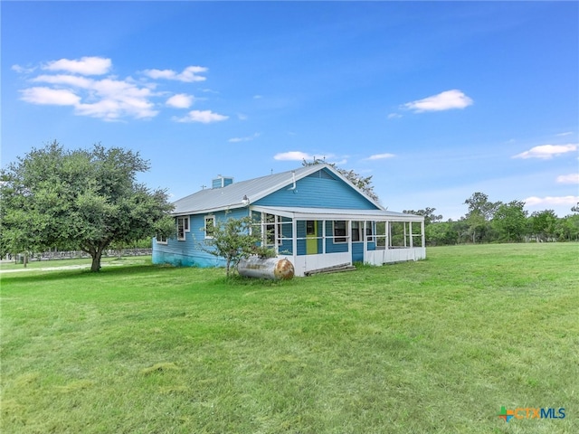 rear view of house with a sunroom and a lawn