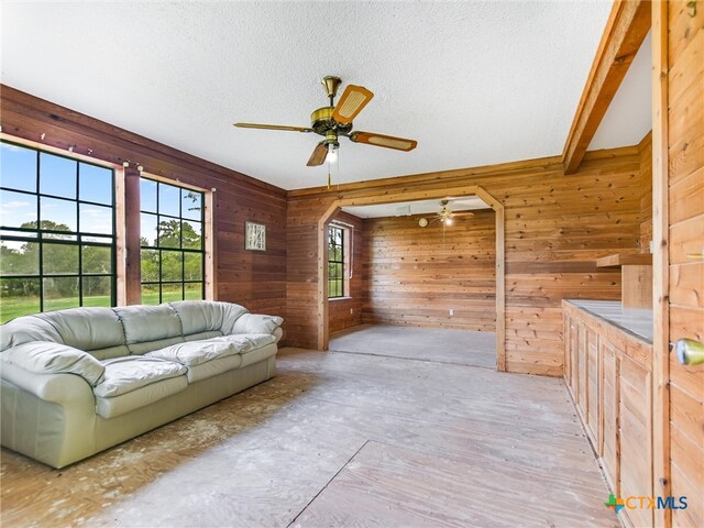 unfurnished living room with wood walls, a textured ceiling, and ceiling fan