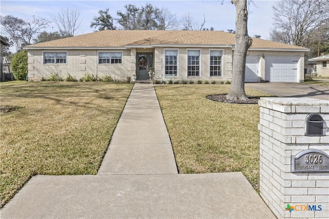 ranch-style home with brick siding, a shingled roof, a garage, driveway, and a front lawn