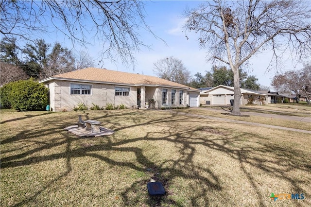 back of property with a garage, brick siding, and a lawn