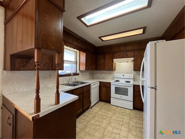 kitchen featuring white appliances, a peninsula, a sink, light countertops, and under cabinet range hood