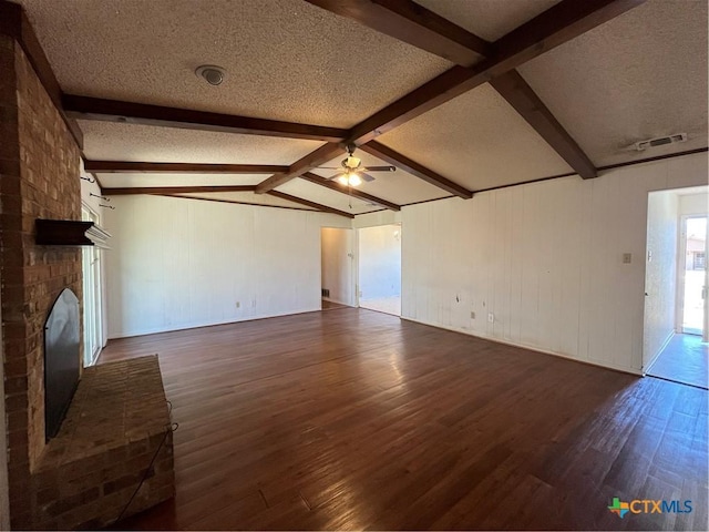 unfurnished living room featuring lofted ceiling with beams, dark wood-style flooring, ceiling fan, a textured ceiling, and a brick fireplace