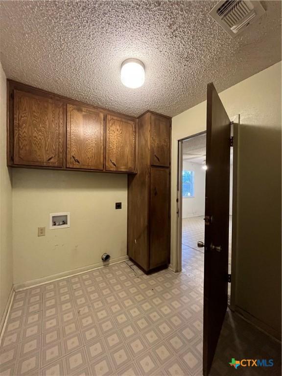 clothes washing area with washer hookup, cabinet space, visible vents, and baseboards