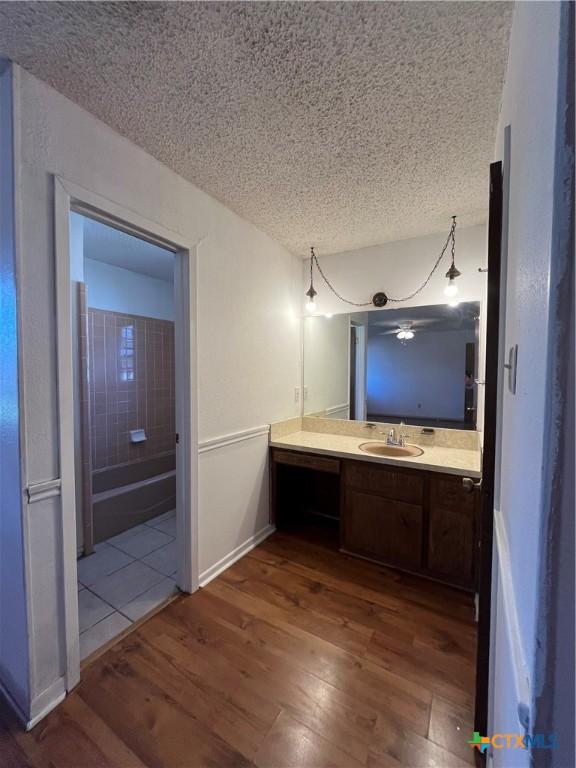 bathroom with a textured ceiling, vanity, baseboards, and wood finished floors