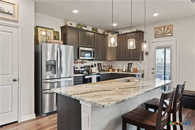 810 Mclaury Cv, Killeen, TX 76542 - kitchen with light stone countertops, dark brown cabinetry, appliances with stainless steel finishes, a sink, and light wood-style floors