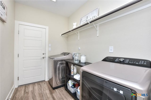 clothes washing area featuring washing machine and clothes dryer and light hardwood / wood-style floors