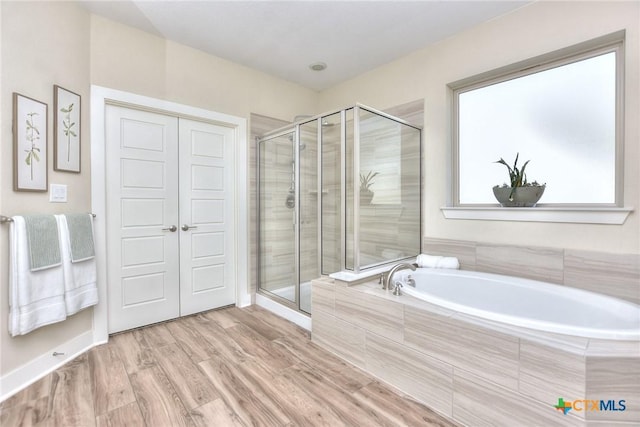 bathroom with hardwood / wood-style floors and shower with separate bathtub