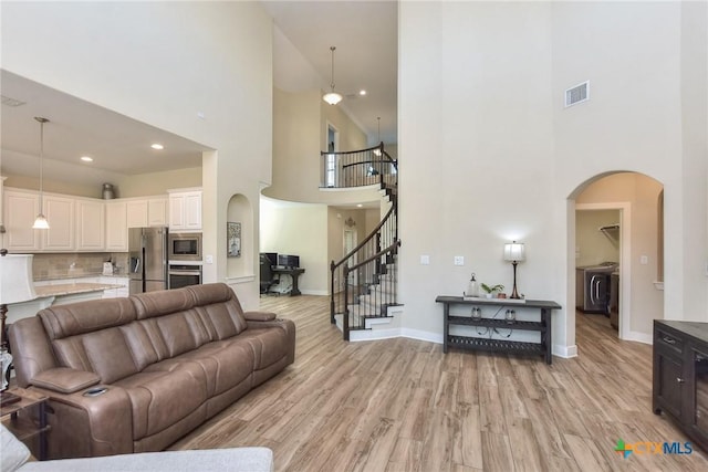 living room featuring light wood-type flooring, washer and dryer, and a towering ceiling