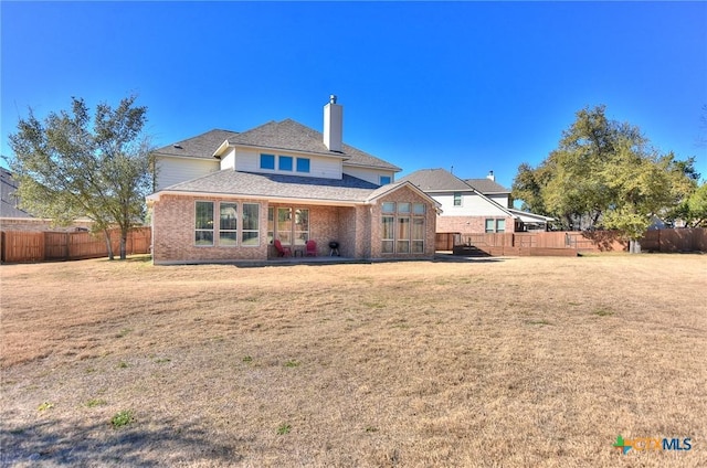 rear view of house with a lawn and a patio