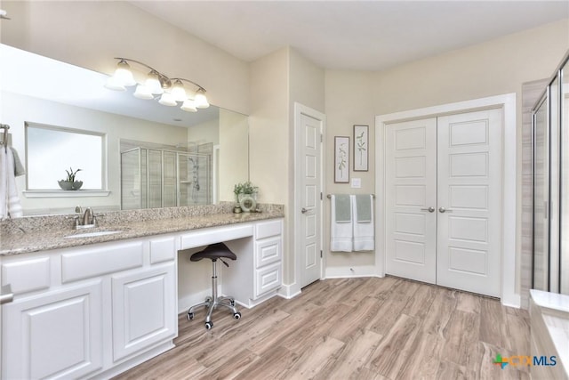 bathroom with a shower with shower door, hardwood / wood-style flooring, and vanity